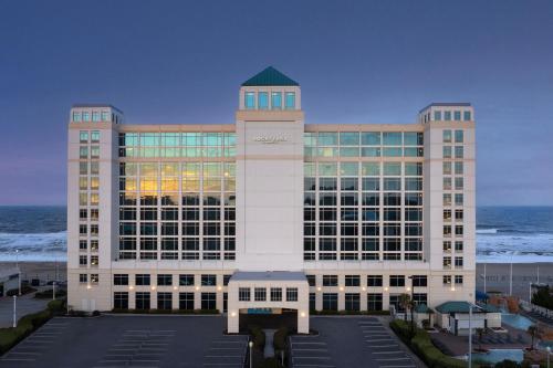 弗吉尼亚海滩弗吉尼亚海滩海滨/北37号大街万怡酒店的一座大型的办公楼,以海洋为背景
