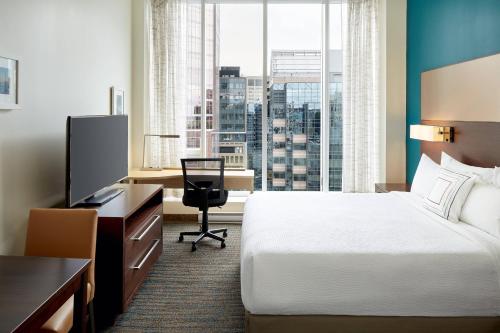蒙特利尔蒙特利尔市中心万豪原住客栈的酒店客房配有一张床、一张书桌和一台电视。