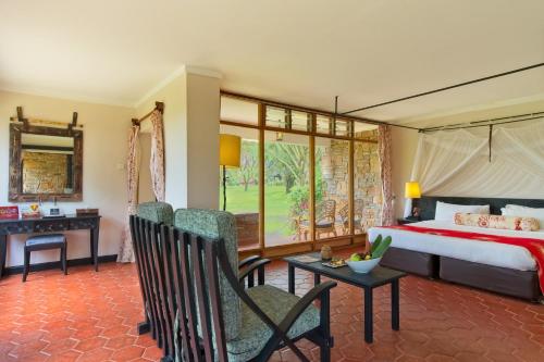 凯科罗克Muthu Keekorok Lodge, Maasai Mara, Narok的卧室配有一张床、一张桌子和椅子