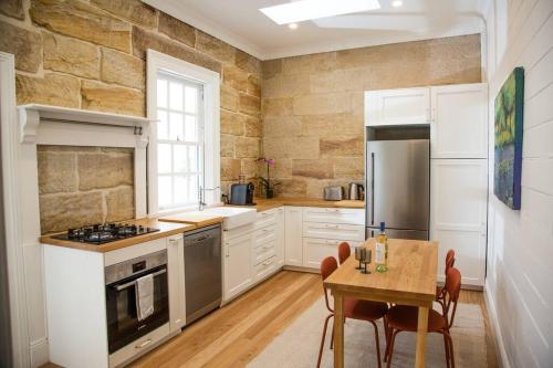 悉尼Balmain Sandstone Cottage的厨房配有白色橱柜和桌椅