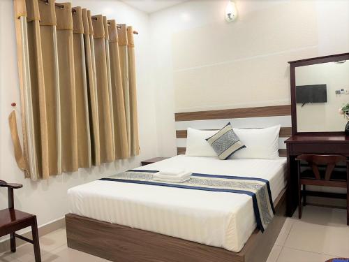 胡志明市DINH DINH 2 AIRPORT HOTEL的一间卧室配有一张带桌子和镜子的床