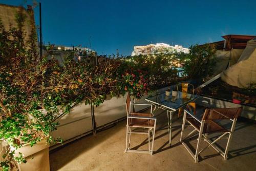 雅典360 view in roof top appartment with patio的阳台上的玻璃桌和两把椅子