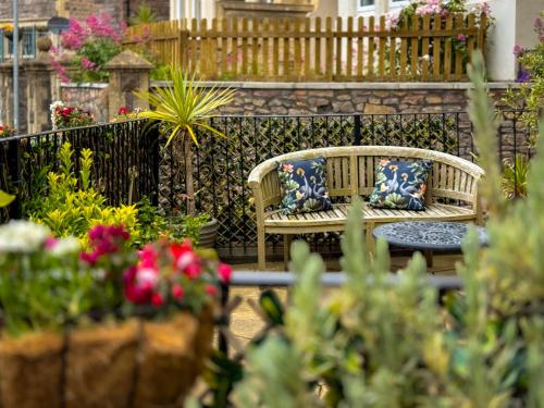 滨海韦斯顿Timbertop Suites - Adults Only的鲜花盛开的花园内两把带枕头的长椅
