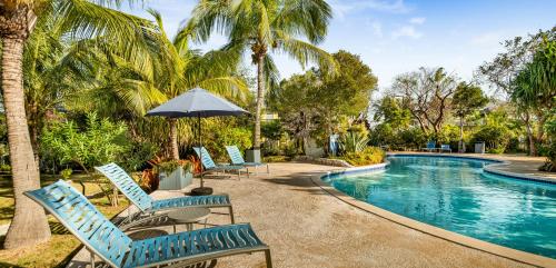 总督港菠萝牧场酒店的一组椅子和一把遮阳伞,位于游泳池旁