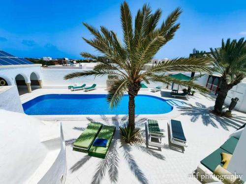 米多恩Maison Leila chambres d hotes的一座带椅子的游泳池,一座房子前面的棕榈树