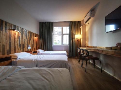 成都Sonderia Hostel & Bar - Lazybones Hostel的一间酒店客房,设有三张床和一台平面电视