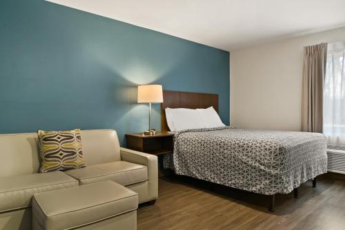 温斯顿·塞勒姆WoodSpring Suites Winston-Salem near Hanes Mall的一间卧室配有一张床、一张沙发和一把椅子