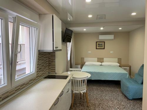 贝尼多姆Aparthotel Pelicano的一间卧室配有一张床铺和一张桌子,还设有一间厨房