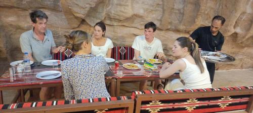 瓦迪拉姆Wadi Rum Aviva camp的一群坐在餐桌上吃食物的人