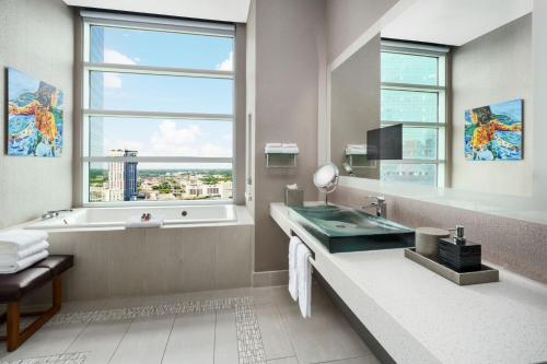 夏洛特AC Hotel by Marriott Charlotte City Center的带浴缸、水槽和窗户的浴室