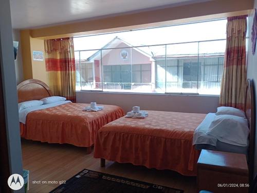 普诺HOSTAL ACUARIUS PUNO的客房设有两张床和大窗户。