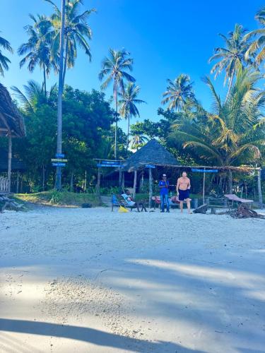 基林多尼Juani beach bungalows的两个人站在棕榈树海滩上