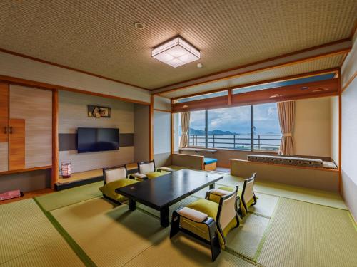 鸟羽户田家酒店的一间带桌椅和电视的用餐室