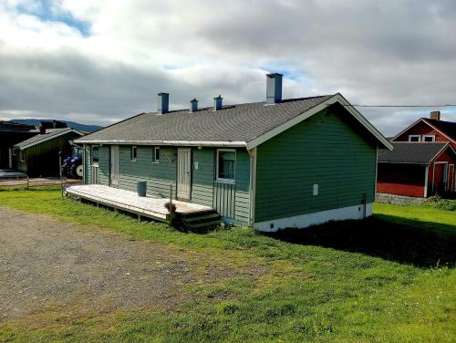KongsfjordKongsfjord Holiday Home的田野上带门廊的绿色房屋