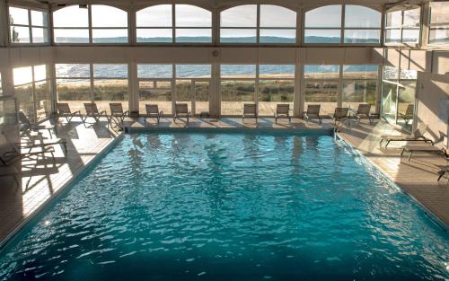 圣特罗让莱班塔拉萨欧勒龙岛诺富特酒店的大楼内带椅子的大型游泳池