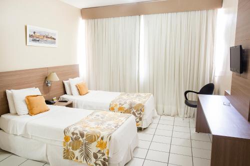 萨尔瓦多Rede Andrade Barra的酒店客房设有两张床和电视。