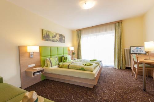 巴特霍夫加施泰因凯泽弗朗茨公寓的一间卧室配有一张带绿色床头板的床和一张书桌