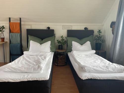 HolenKoselig garasjeloft!的客房内的两张床、白色的毯子和枕头