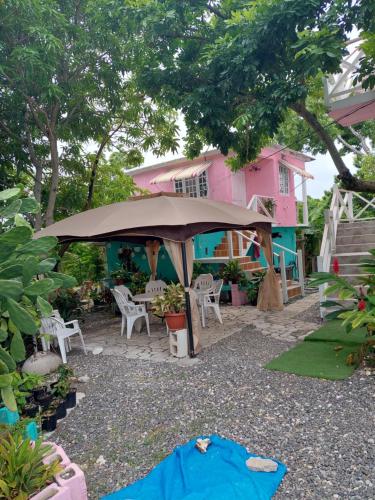 安东尼奥港Alex's Place - Tim Pappies的粉红色的房子,前面有一把大伞
