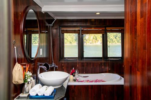 下龙湾传奇下龙私人邮轮酒店 - 哈亚巡游管理局的带浴缸和水槽的浴室以及2扇窗户。