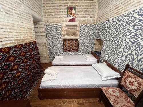 布哈拉Ohun Caravansarai 16 th century的一间设有两张床铺的客房,位于一个墙上