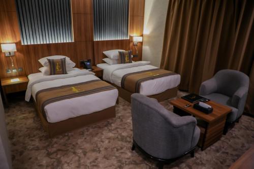 麦地那فندق ايي E Hotel的酒店客房,配有两张床和两把椅子
