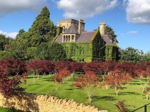 科舍姆The Rudloe Near Bath - Marco Pierre White的一座常春藤覆盖的建筑,石墙和树木