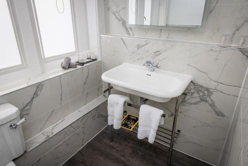阿克菲尔德Horsted Place Hotel的浴室设有白色水槽和大理石墙壁。