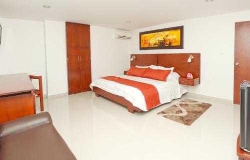 布卡拉曼加安迪诺酒店的一间卧室配有一张床、一张书桌和一台电视