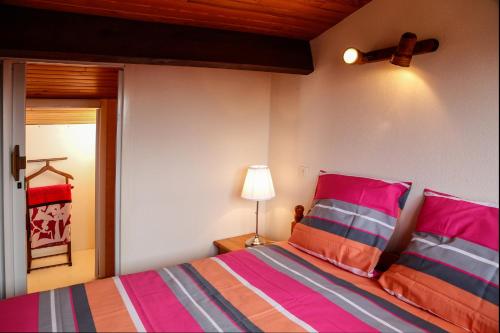 布科·莱斯白老城阿基坦公寓的一间卧室配有带粉色和橙色枕头的床