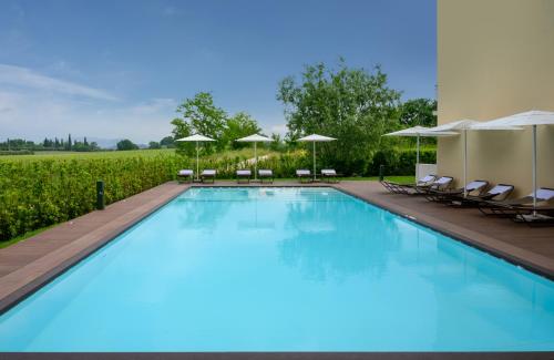 拉齐塞Leonardo Hotel Lago di Garda - Wellness and Spa的一个带椅子和遮阳伞的大型游泳池
