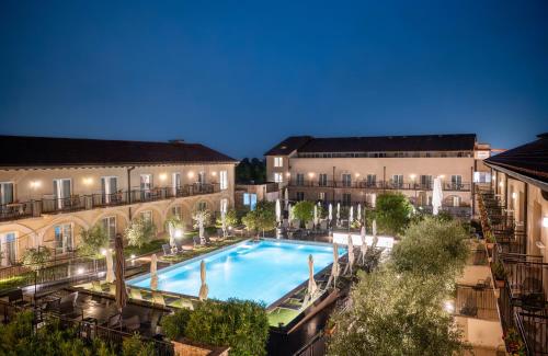 拉齐塞Leonardo Hotel Lago di Garda - Wellness and Spa的两栋建筑的庭院内的一个室外游泳池