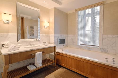 伦敦Corinthia London的带浴缸、水槽和镜子的浴室