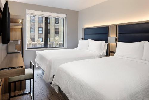 纽约纽约切尔西快捷假日酒店的酒店客房设有两张床和窗户。