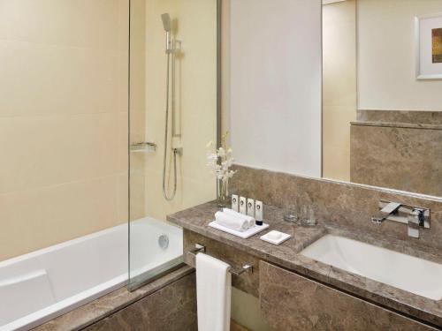 吉达Mövenpick Hotel Tahlia Jeddah的带浴缸、水槽和淋浴的浴室
