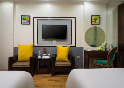 河内Bella Premier Hotel & Rooftop Skybar的客厅配有黄色枕头和电视