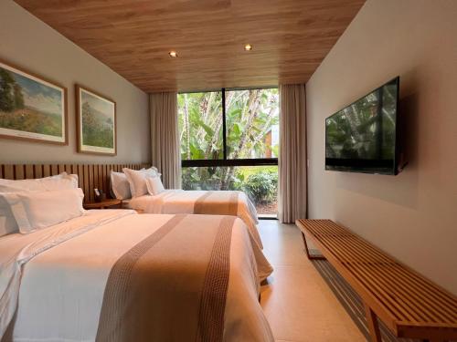 彼得罗波利斯Casa Marambaia Hotel的配有电视和窗户的客房内的两张床