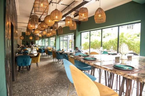 拉各斯河豚酒店的餐厅设有长桌子、椅子和窗户。