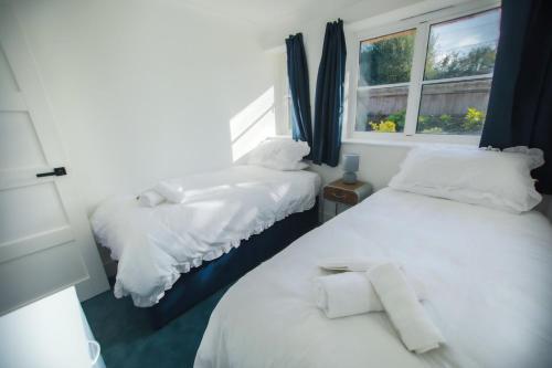 WestfieldRose Cottage的一间卧室设有两张带白色床单的床和窗户。