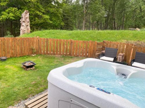 BalnaldKaoglen-Stags-Hot tub-Cairngorms-Pet Friendly的庭院内的热水浴池,配有两把椅子