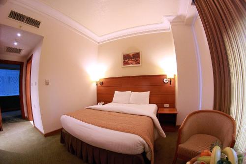 安曼Sadeen Amman Hotel的配有一张床和一把椅子的酒店客房