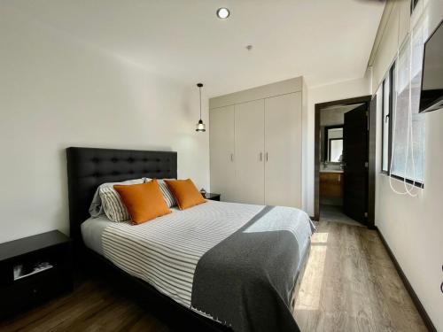 基多&ARBAT Quito Republlica del Salvador Alquiler por días的一间卧室配有一张带橙色枕头的大床
