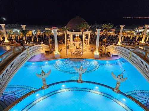 阳光海滩Imperial Palace Hotel的夜间游泳池,人们跳水