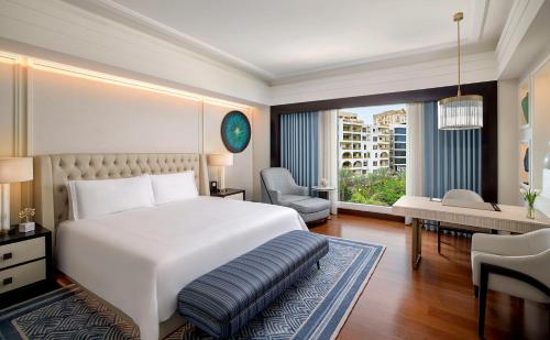 开罗Waldorf Astoria Cairo Heliopolis的卧室配有一张白色大床、一张桌子和椅子