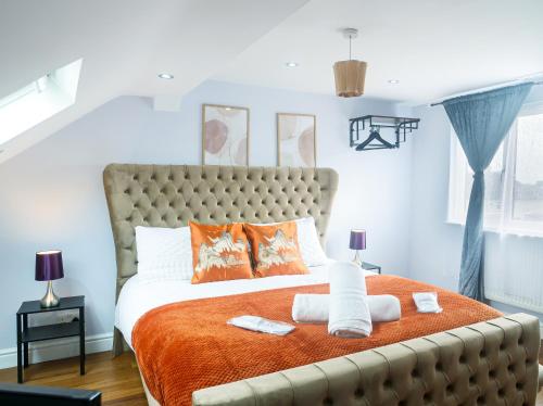 贝克斯利黑思Royal Luxe 6 Bed House in London的一间卧室配有一张带橙色毯子的大床