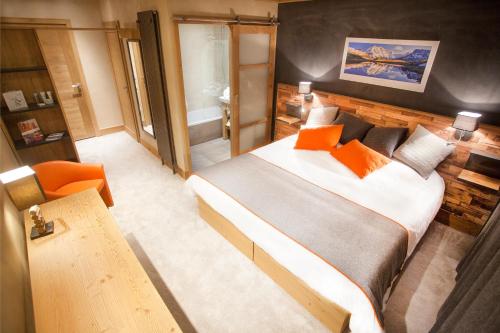 琴山朗勒堡圣查尔斯瓦尔塞尼酒店的一间卧室配有一张大床和一张橙色椅子