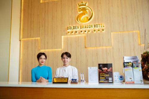 胡志明市Golden Dragon Hotel Sai Gon的两个人站在房间里柜台