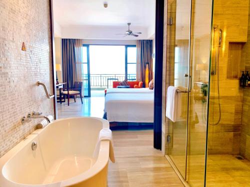 岘港岘港皇冠假日酒店的带浴缸的浴室和1间带1张床的卧室