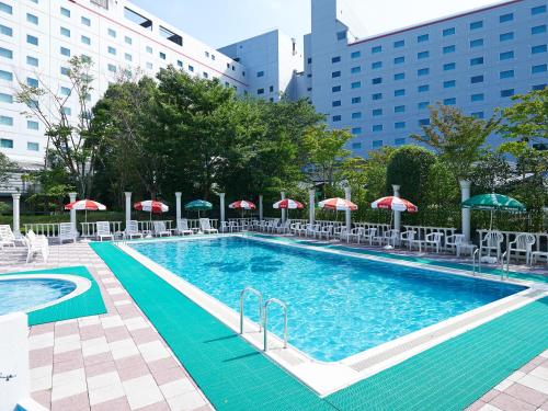 成田日航国际酒店的一个带遮阳伞和椅子的大型游泳池