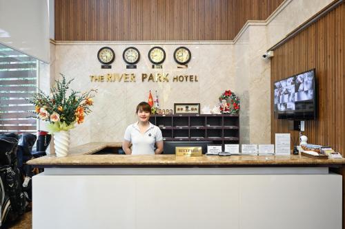 胡志明市The River Park Hotel的一位站在旅行广场酒店柜台后面的妇女